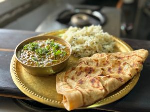 A close-up of a delicious Indian meal with paratha, curry, and rice on a golden plate.